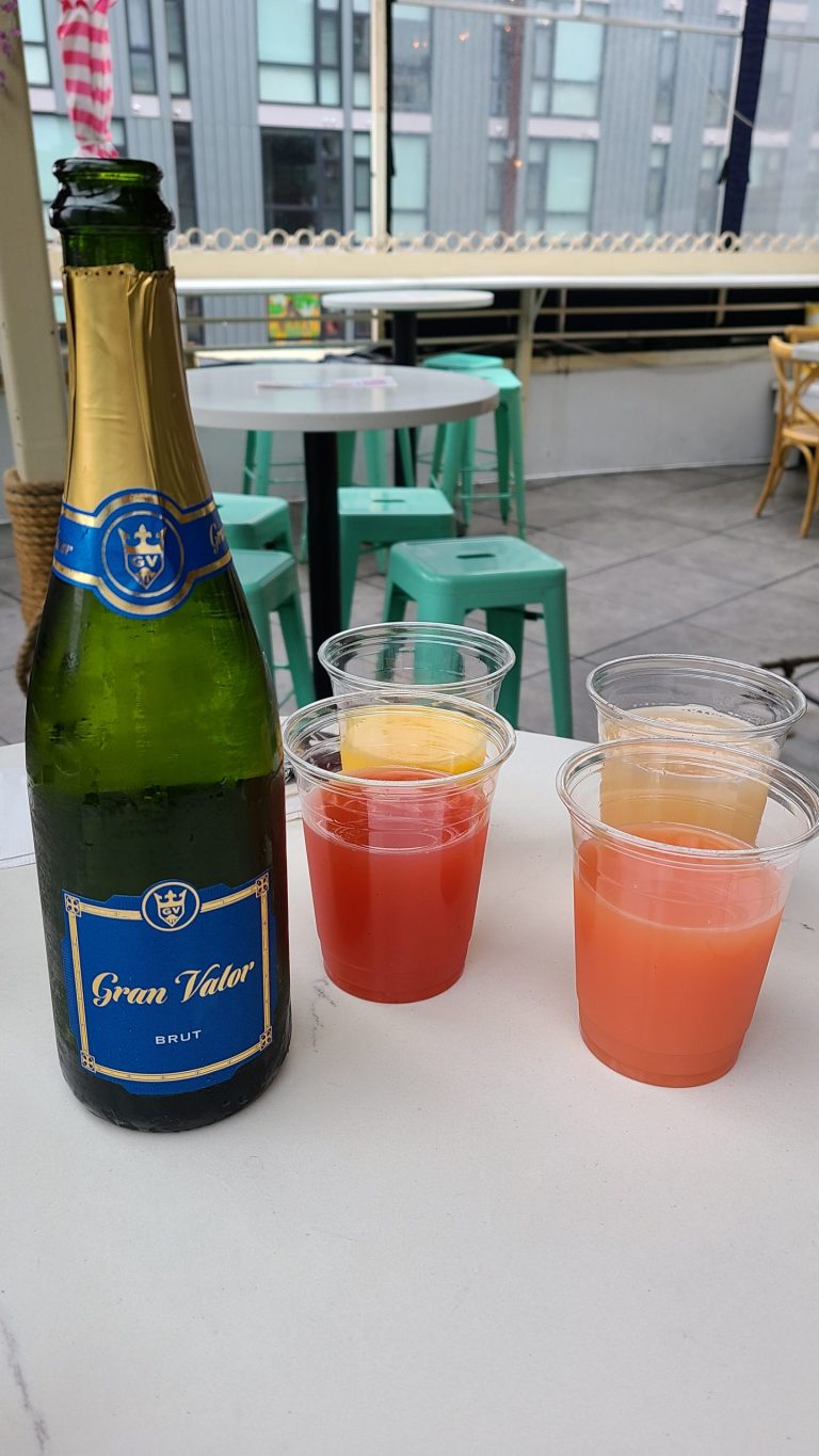 Bottle of champagne with 4 juice choices in plastic cups