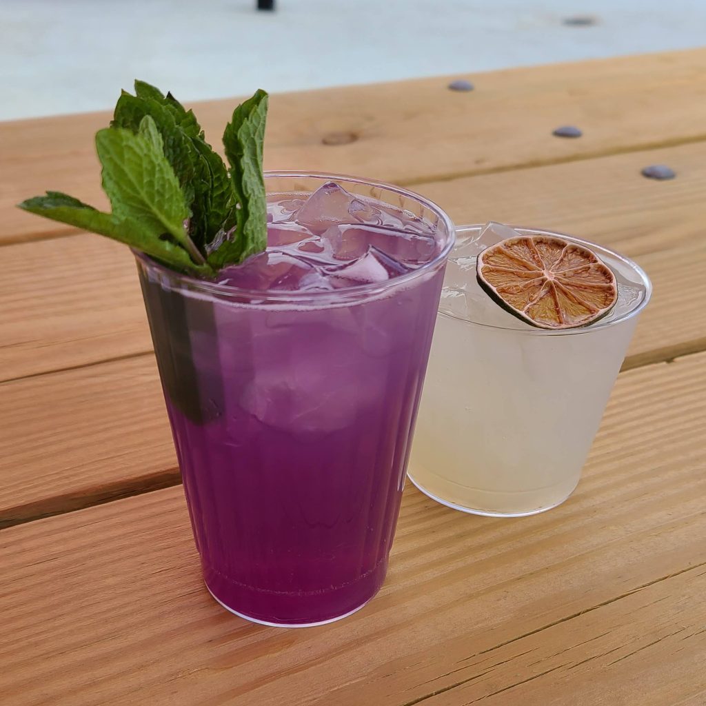 A purple drink and a yellow drink on a table
